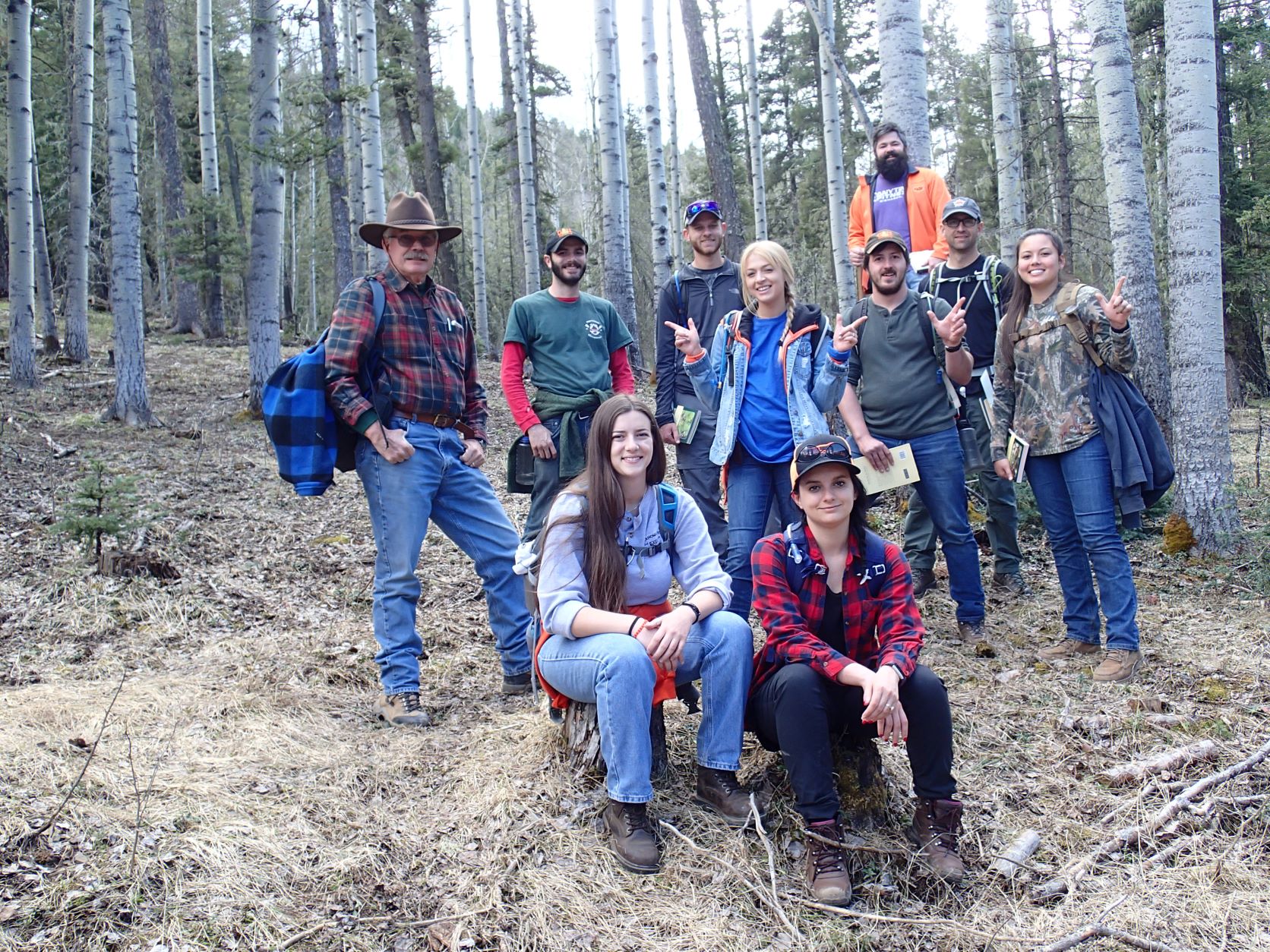A group of 10 people standing together in the woods.