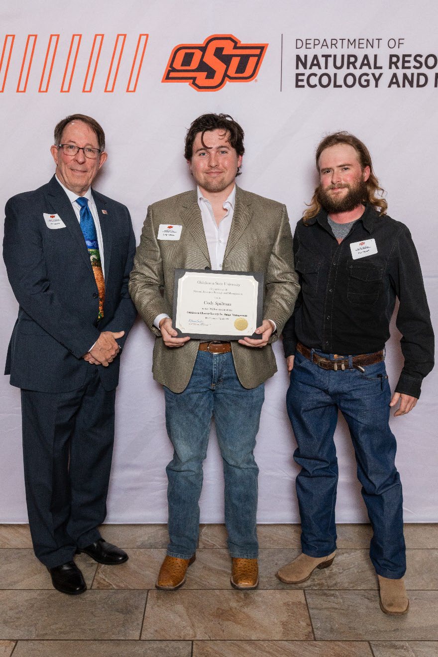 Cody is accepting his award from Jack next to Dr. Jim Ansley.