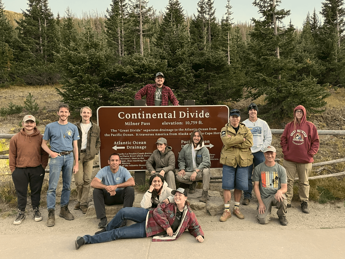 Students of the Society for American Foresters at the Continental Divide with green pine trees in the background